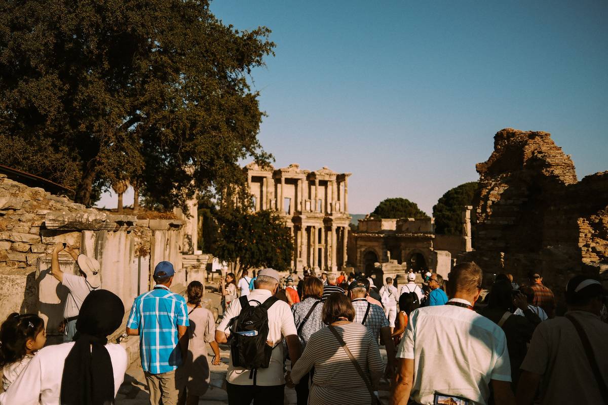 A group of visitors walking down Curetes Street in Ephesus toward the Library of Celsus in the early evening sun