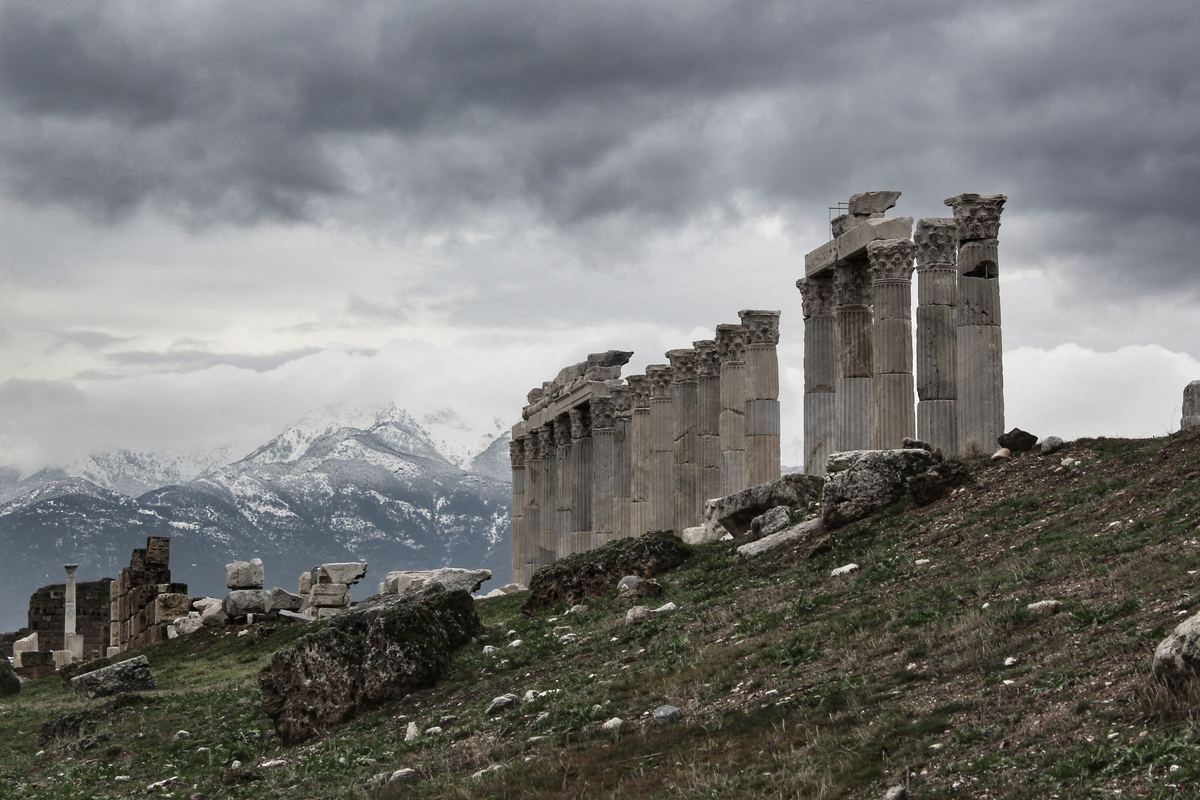 Fluted Corinthian columns on a hillside at Laodicea under storm clouds, with snow on the mountains behind